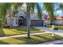 Home with lush lawn and tidy landscaping, and a driveway leading to the garage at 7135 Royal George Ct, Wesley Chapel, FL 33545