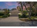 Lovely home at twilight features a paved driveway, tile roof, lush landscaping, and an attached two-car garage at 866 Placid Lake Dr, Osprey, FL 34229