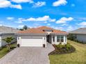 Inviting single-story home with a tile roof, paver driveway, manicured lawn, and beautiful landscaping at 10240 Beach Dune Dr, Englewood, FL 34223