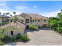 Elegant two-story home with a tiled roof, porte-cochere, and spacious paver driveway at 1930 Bayshore Dr, Englewood, FL 34223