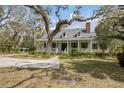 Lovely two-story home with front porch, framed by mature trees and beautiful landscaping at 4871 Hoyer Dr, Sarasota, FL 34241