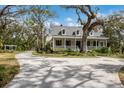 Beautiful two-story home with inviting front porch, set amidst lush landscaping and mature trees at 4871 Hoyer Dr, Sarasota, FL 34241