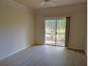 Bright living room with wood-look floors, ceiling fan, and sliding glass doors with a view of greenery at 5168 Northridge Rd # 102, Sarasota, FL 34238
