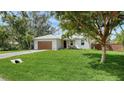 Charming single-story home with a well-manicured lawn, modern wood garage door, and lush tropical landscaping at 6136 Hollywood Blvd, Sarasota, FL 34231