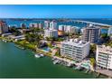 Stunning aerial view of waterfront condos with docks, pools, and city views in the distance at 650 Golden Gate Pt # 602, Sarasota, FL 34236