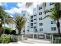 White modern condo building featuring tropical landscaping with palms, and secure gated entrance at 650 Golden Gate Pt # 602, Sarasota, FL 34236