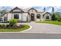 Beautiful exterior elevation showcasing stone accents, a tile roof, and a circular driveway with lush landscaping at 1575 Eastbrook Dr, Sarasota, FL 34231