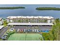 Aerial view showcases the building, covered parking, and tennis courts, with a glimpse of the waterway at 4310 Falmouth Dr # 304, Longboat Key, FL 34228