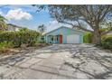 Charming coastal home featuring a well-manicured lawn, beautiful pavers, and a bright red front door at 511 68Th St, Holmes Beach, FL 34217