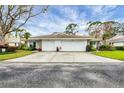 A well-maintained home featuring a double garage door and a spacious driveway with beautiful landscaping at 5614 Garden Lakes Dr, Bradenton, FL 34203