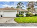 Inviting home featuring a large garage door, and a well-manicured lawn with beautiful landscaping at 5614 Garden Lakes Dr, Bradenton, FL 34203