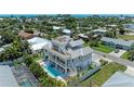 Aerial view of a luxurious three-story home with a rooftop terrace, pool, and lush landscaping, embodying coastal elegance at 215 83Rd St, Holmes Beach, FL 34217