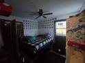Bedroom with a black-and-white plaid bedspread, ceiling fan, and small pictures on the wall at 303 60Th W Ave, Bradenton, FL 34207