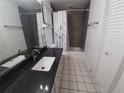 Bathroom featuring a dark granite counter, white floors and a shower with grey subway tile at 4031 Iola Dr, Sarasota, FL 34231
