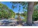 Lush backyard overlooking a serene lake, with verdant landscaping and mature trees at 417 Tortuga Dr, Nokomis, FL 34275