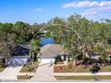 Aerial view of a home with a large yard, nearby lake, mature trees, and a two-car garage at 4627 Breezy Pines Blvd, Sarasota, FL 34232
