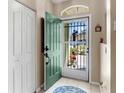 Inviting foyer featuring tile flooring, coat closet, security screen door, and a view of the landscaped front yard at 4627 Breezy Pines Blvd, Sarasota, FL 34232