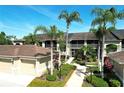Condominium exterior featuring lush landscaping, palm trees and attached garages under a bright blue sunny sky at 5211 Mahogany Run # 113, Sarasota, FL 34241