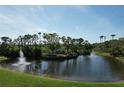 Scenic aerial of landscaped pond with fountains and lush green spaces and a community sign at 5211 Mahogany Run # 113, Sarasota, FL 34241