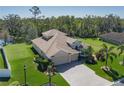 Beautifully landscaped home with a three-car garage, long brick driveway, green lawn, and a serene view of the water and wooded area at 5412 72Nd E Ter, Ellenton, FL 34222