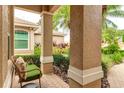Cozy front porch with a wicker chair overlooking the lush landscaping and brick-paved walkway at 6103 Aviary Ct, Bradenton, FL 34203