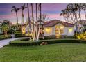 Charming front yard with lush lawn and manicured shrubbery and a beautiful home exterior at twilight at 612 Weston Pointe Ct, Longboat Key, FL 34228
