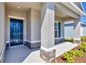 Inviting front porch featuring stone accents and a stylish blue front door at 818 170Th E Ct, Bradenton, FL 34212