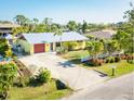 Charming yellow home featuring a well-manicured lawn, a driveway, and mature landscaping at 9031 Hilolo Ln, Venice, FL 34293