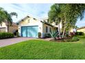 Charming yellow home with a turquoise garage door, lush landscaping and beautiful palm trees at 1022 Overlook Ct, Bradenton, FL 34208