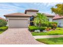 Charming single-story home with a brick paver driveway and well-manicured tropical landscaping at 1290 Cielo Ct, North Venice, FL 34275