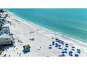 Expansive beach view with blue umbrellas and chairs, white sand, and ocean waves at 1325 Gulf Dr N # 248, Bradenton Beach, FL 34217