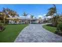 Charming single-story home featuring a lush lawn, mature trees, and a paver driveway leading to a bright entry at 1806 Caribbean Dr, Sarasota, FL 34231