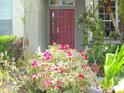Charming front entrance with a red door surrounded by vibrant flowers and lush tropical landscaping at 315 Londonderry Dr, Sarasota, FL 34240