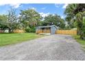 Inviting blue home with wood deck, large gravel driveway and fenced yard surrounded by mature trees at 3561 Elfers Pkwy, New Port Richey, FL 34655
