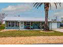 Charming teal home featuring a metal roof, covered porch, and a mature palm tree in the front yard at 4524 106Th W St, Bradenton, FL 34210