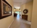 Hallway with tile flooring leads to living areas, adorned with artwork and furniture at 5962 Roseto Pl, Sarasota, FL 34238