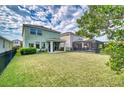 Spacious backyard featuring lush green grass, a covered patio, and secure fencing at 6136 Voyagers Pl, Apollo Beach, FL 33572