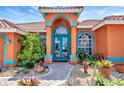 Charming home entrance with a colorful exterior, arched doorway, and vibrant landscaping at 7118 42Nd E Ct, Sarasota, FL 34243