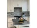 A well-lit kitchen with white cabinetry, stainless steel appliances, and a unique backsplash at 728 41St St St, Sarasota, FL 34234