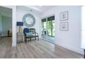 Hallway featuring a large round mirror, a sliding glass door leading to the screened lanai, and wood-look floors at 800 Everest Rd, Venice, FL 34293