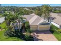 Aerial view of a charming one-story home with a brick driveway, three-car garage, and lush landscaping with palm trees at 8861 17Th Avenue Nw Cir, Bradenton, FL 34209