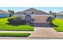 Charming single-Gathering home featuring a brick driveway, lush lawn, and manicured landscaping at 1014 Calico Gln, Bradenton, FL 34212