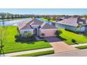 Inviting single-Gathering home features a brick driveway, lush lawn, and well-maintained landscaping near a lake at 1014 Calico Gln, Bradenton, FL 34212