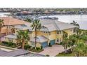 Side exterior view of the yellow house with palm trees, a marina, and water in the background at 1235 Riverscape St # 1235, Bradenton, FL 34208