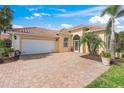 Inviting home with a brick paver driveway, two-car garage, and lush landscaping at 13320 Coluccio St, Venice, FL 34293