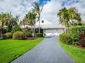 Charming single-story home featuring a paved driveway and lush tropical landscaping, creating a serene and inviting curb appeal at 1511 N Lake Shore Dr, Sarasota, FL 34231