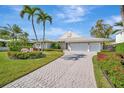 Stunning single-story home featuring a paved driveway and lush landscaping with palm trees at 1511 N Lake Shore Dr, Sarasota, FL 34231