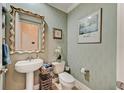 Stylish powder room with elegant wallpaper, pedestal sink, decorative mirror, and a modern toilet for guests' convenience at 2512 61St E Ave, Ellenton, FL 34222