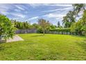 Expansive backyard with lush green grass, bordered by a wooden fence and mature trees at 2566 Tulip St, Sarasota, FL 34239