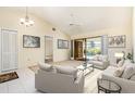 Cozy living room with neutral décor, tile flooring, ceiling fan, and sliding glass doors leading to a screened patio with pool view at 31 Bunker Rd, Rotonda West, FL 33947